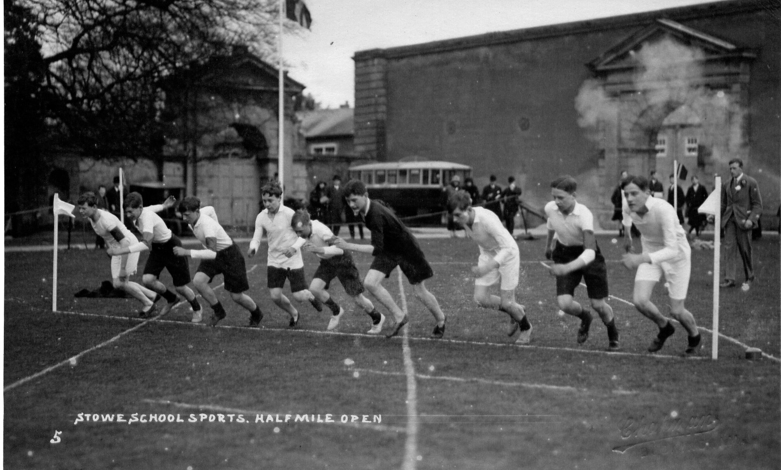 A group of nine young boys approx. between 13-15 start the Stowe school half mile run. The image is from the 1930s, is in black and white. The boys wear black and white shorts with t-shirts and running shoes.