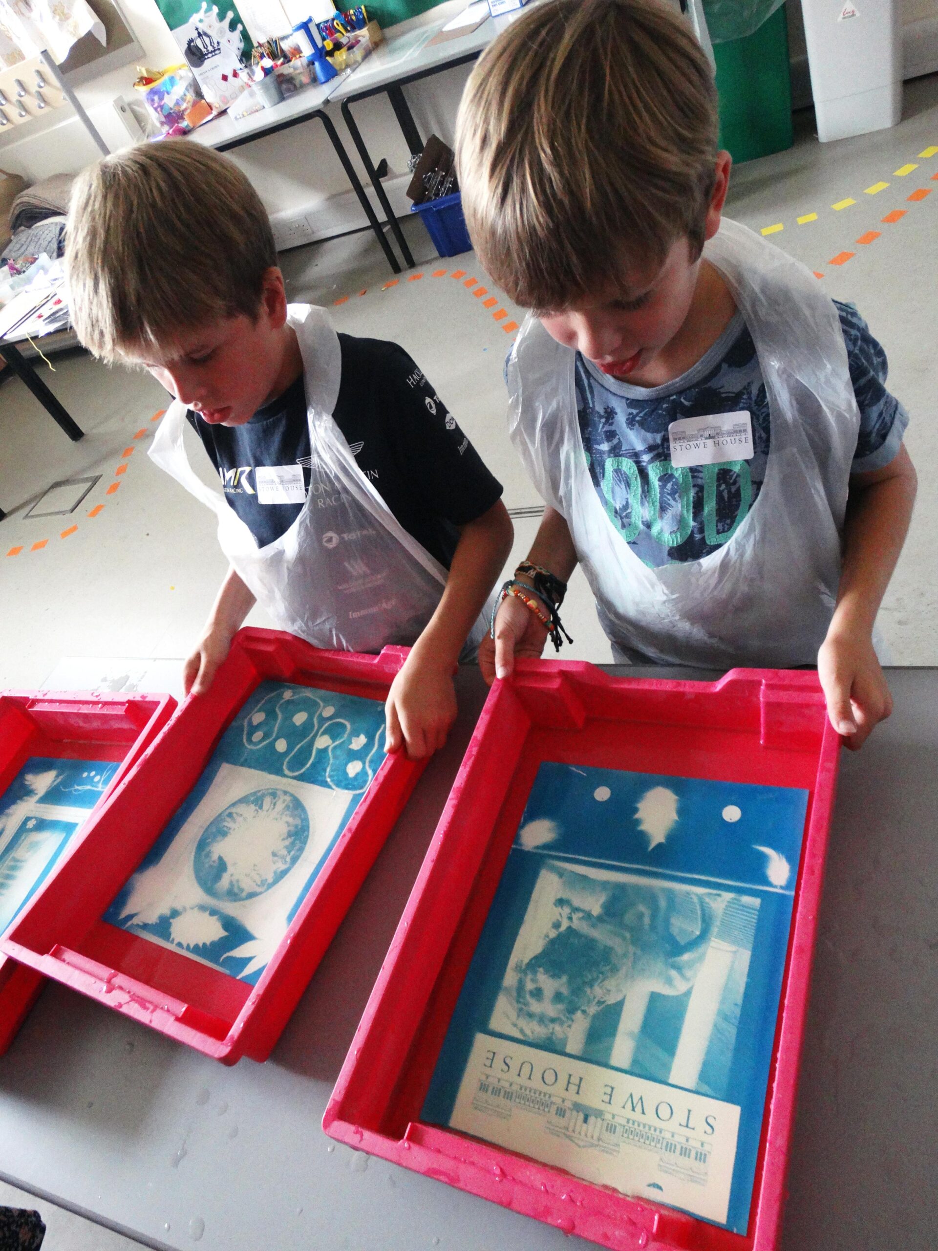 Two young boys approx 10, hold trays as they complete a cyanotype art workshop
