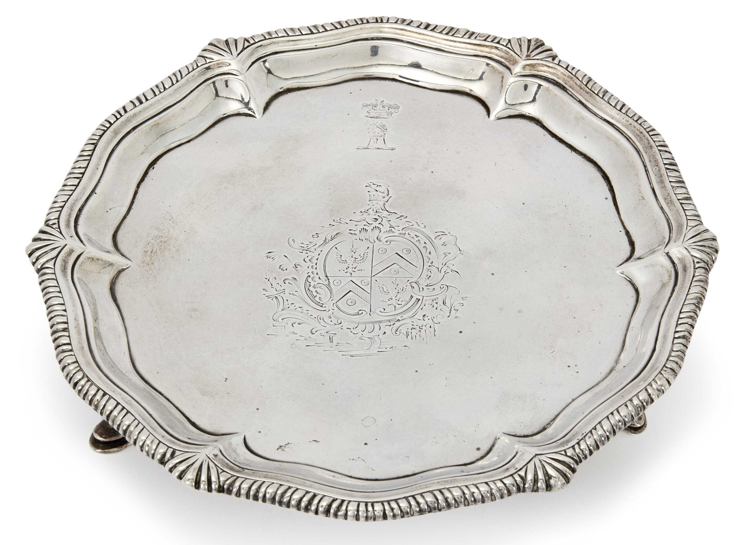 A large oval silver plate with decorate rim and engraved with a large crest of arms